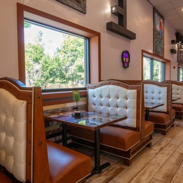 Row of brown and white booths with tables next to windows at Pedros Tacos & Tequila Bar.