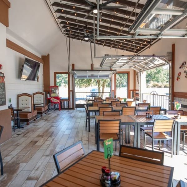Spacious dining room at Pedros Tacos & Tequila Bar with wooden tables, chairs, and open garage doors.